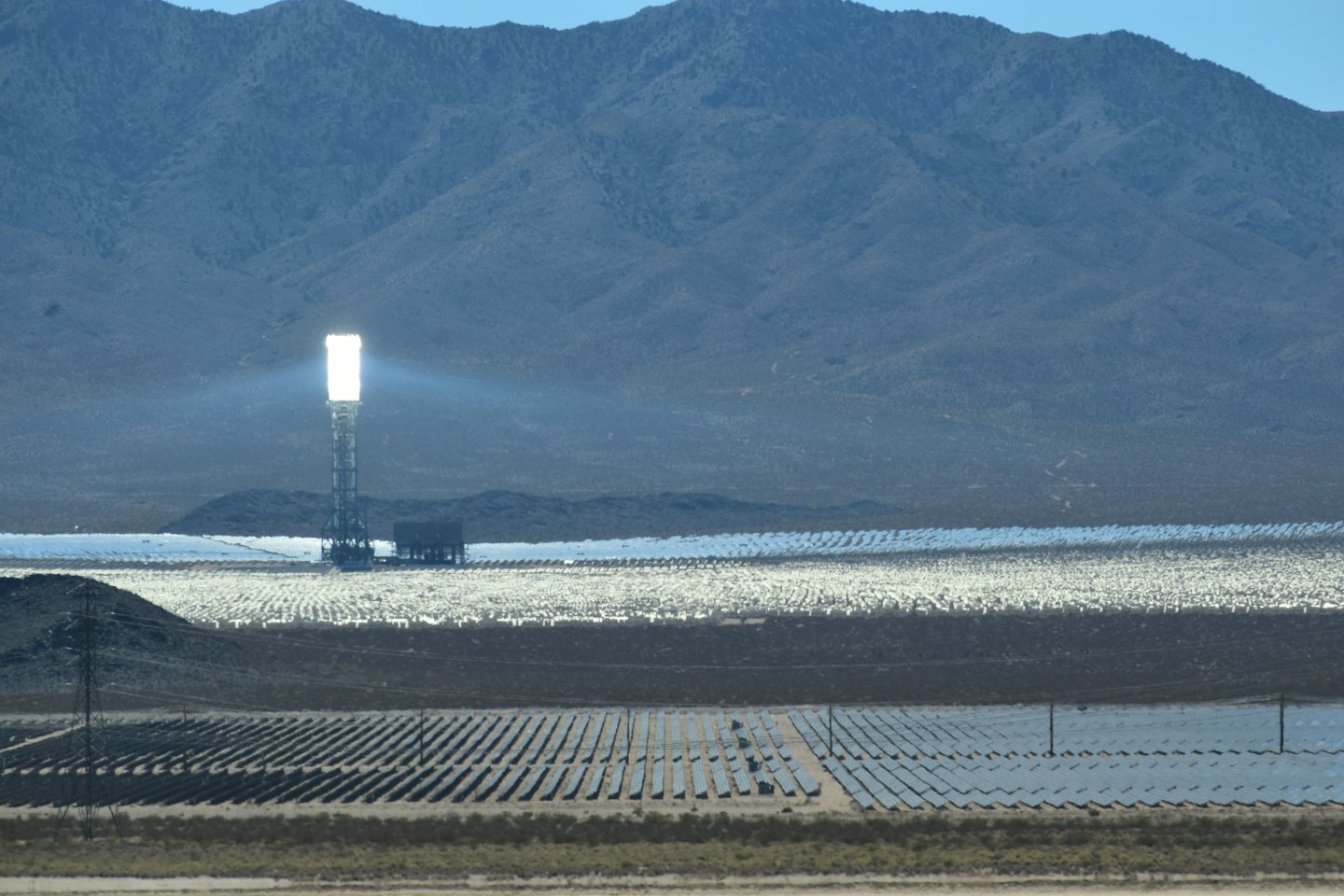 Solar power plant with a central tower and heliostat mirrors in the desert.