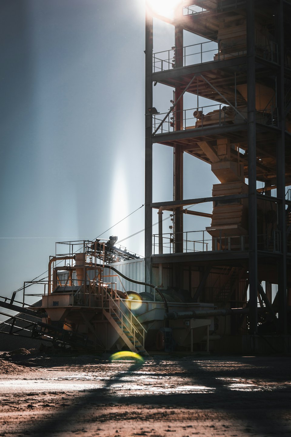 Industrial plant structures and conveyor belts stand under a clear sky.