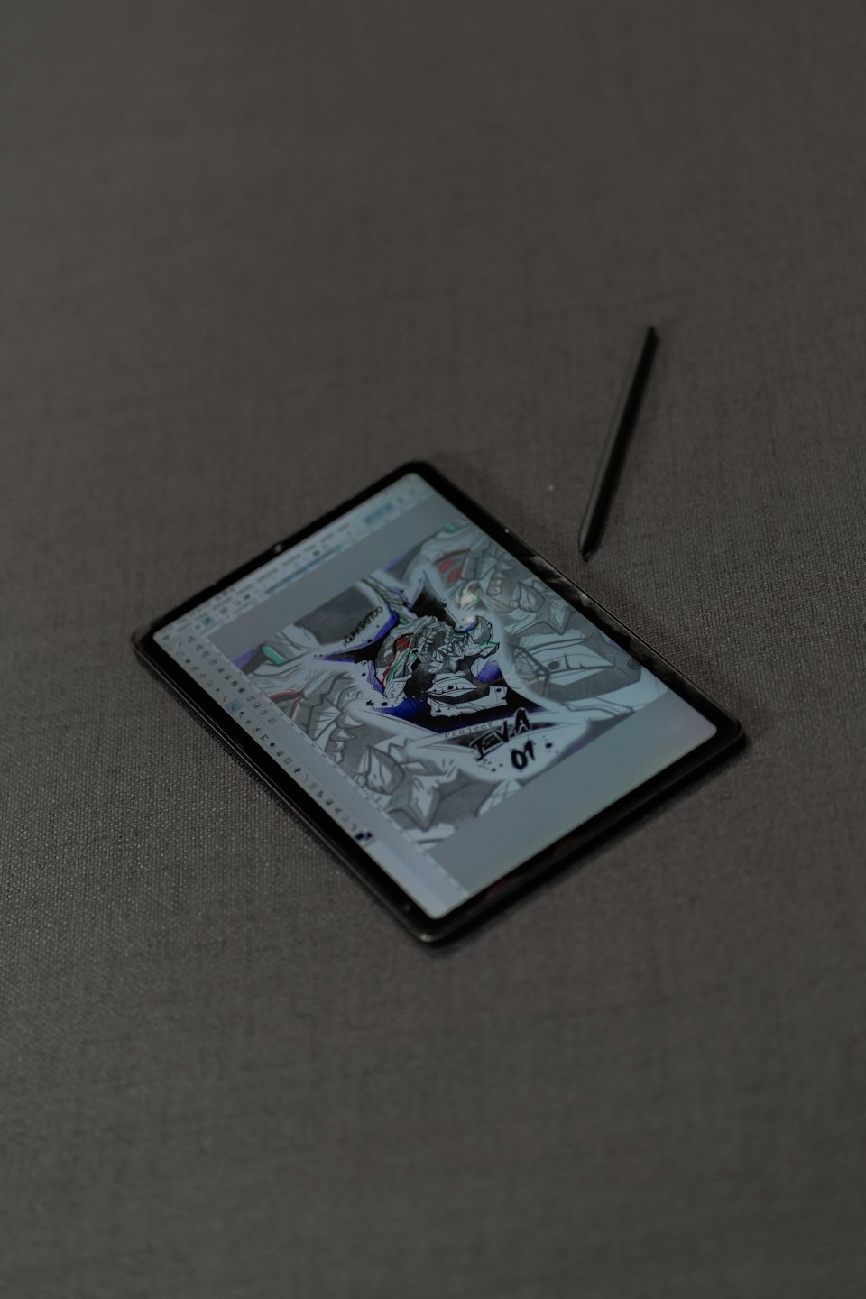 Stylus rests beside a tablet displaying a digital robot illustration.